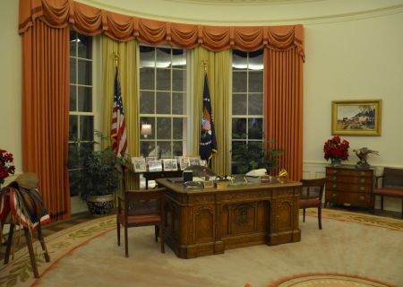 A spacious, warmly lit living room with a central coffee table, cherishing vintage furniture, potted plants, and large windows. End.