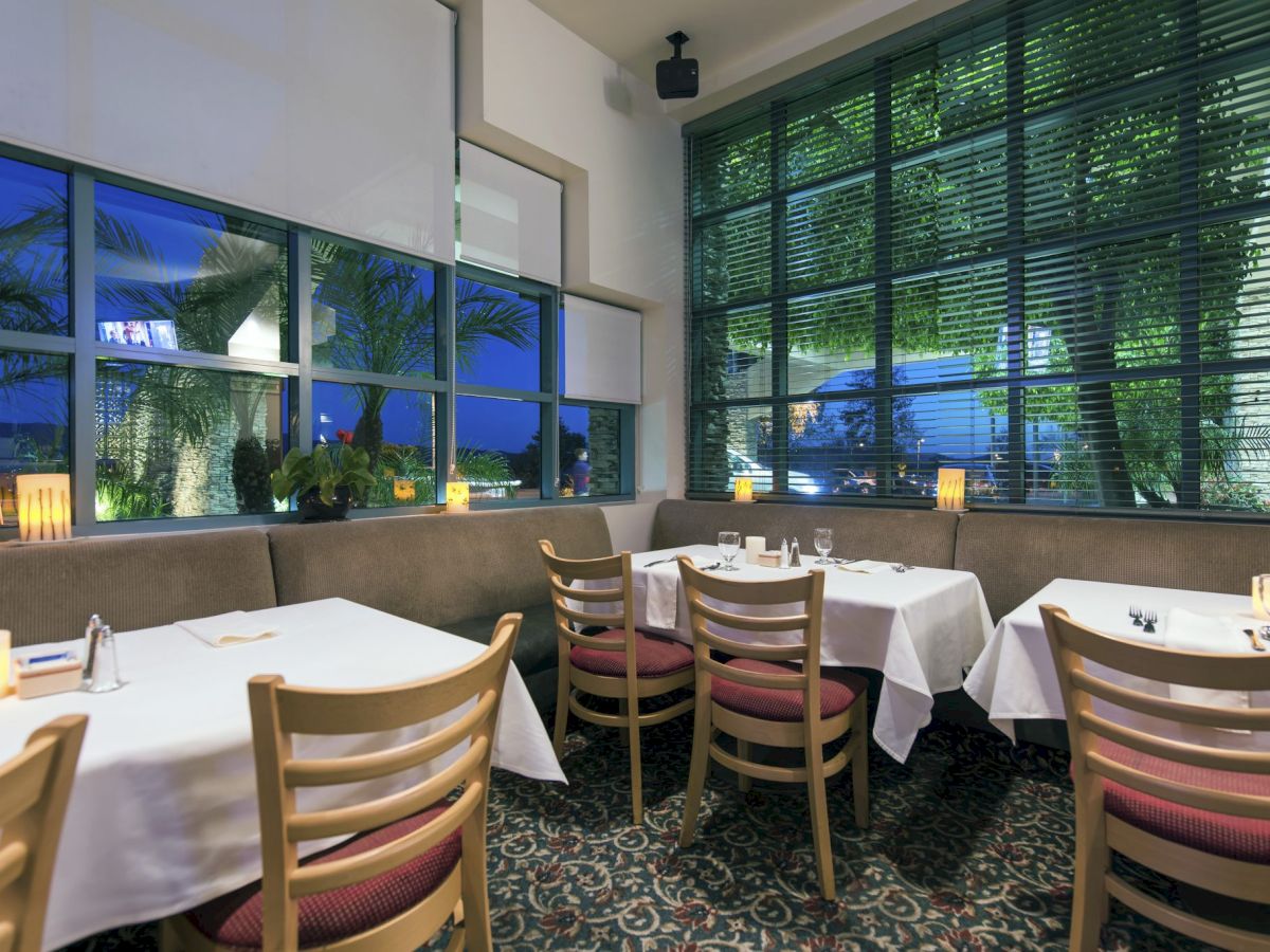 A cozy restaurant with white-cloth tables, wooden chairs, soft candlelight, large windows, and a calm, intimate dining atmosphere.