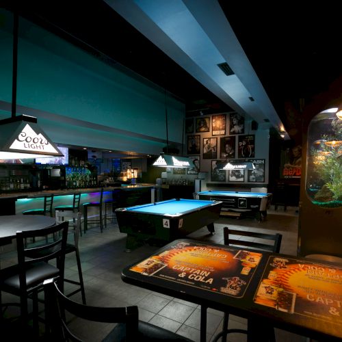 A dim billiards hall with pool tables, neon signs, and stools, cozy lights, and a bar area in the background under teal and orange hues.